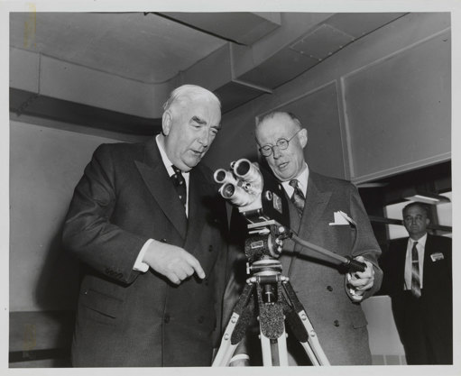 Two men looking a small movie camera