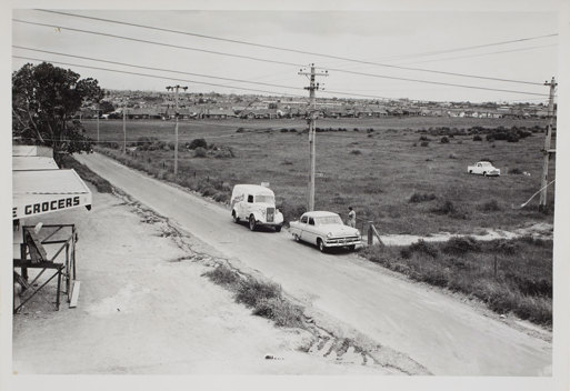 Two cars on country road with fields in background