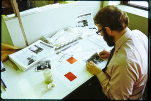 Man sitting at a desk gluing images to a newletter