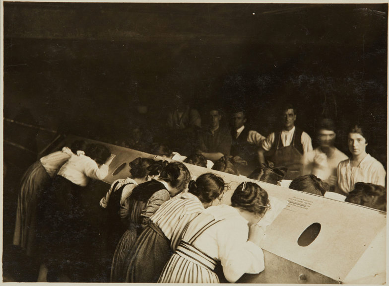 Line of people with their faces pressed into slopped openings