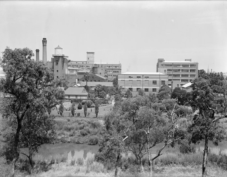 River in foreground with multi-story industrial building on far bank.