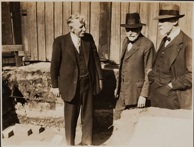 Three men in suits, two wearing hats.