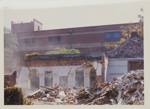 Building rubble in foreground, partially demolised brick building in background