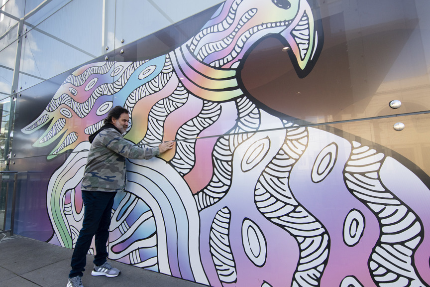 An artist touches his hand to his giant image of an eagle  