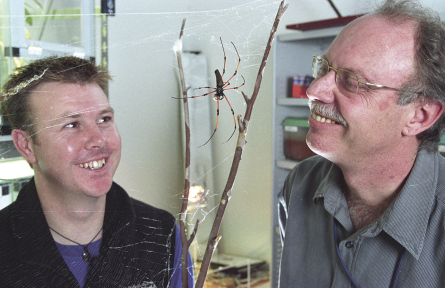 two men face to face with a spider 