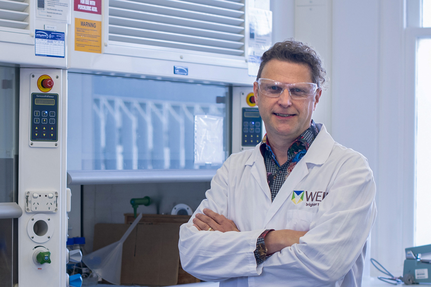 a man in a laboratory wearing glasses and a white coat