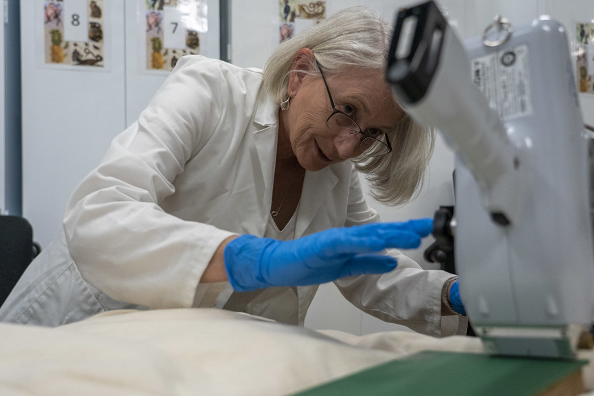 a woman in a lab coat touches a white scanner that is pointed at a green book