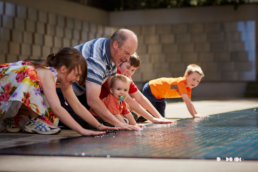 family on knees looking at the Tribute Garden in Immigration Museum.