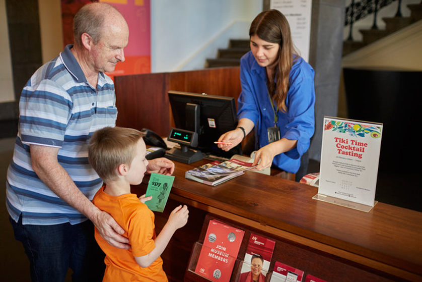 Visitor with a child at the ticketing desk in Immigration Museum.