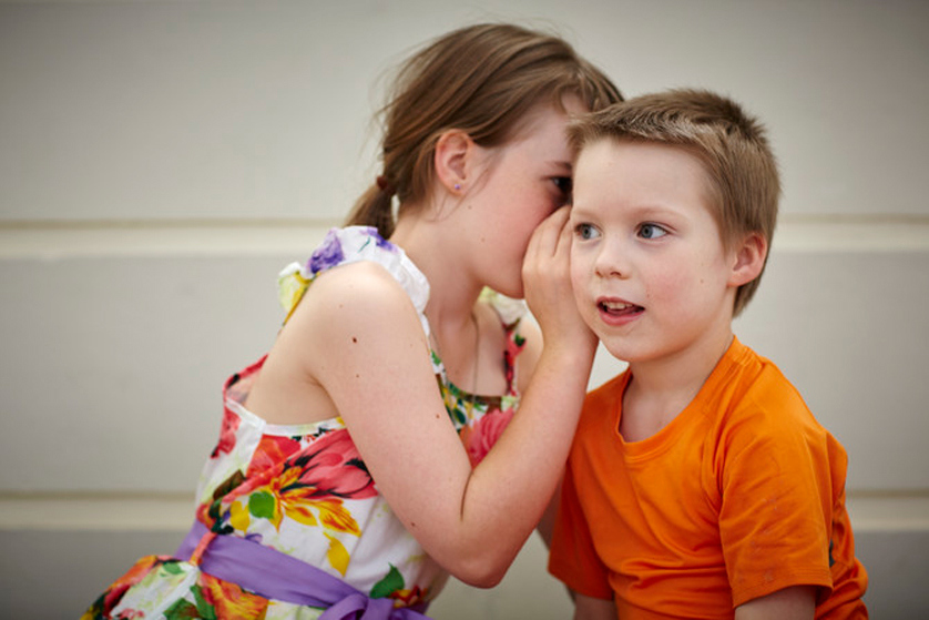 Girl whispering to a boy's ear