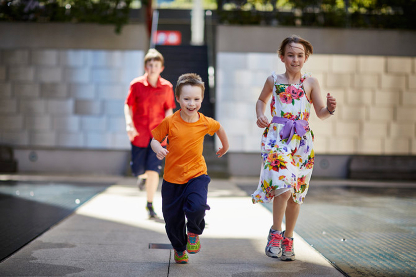 Girl and boy running in Tribute Garden in Immigration Museum.