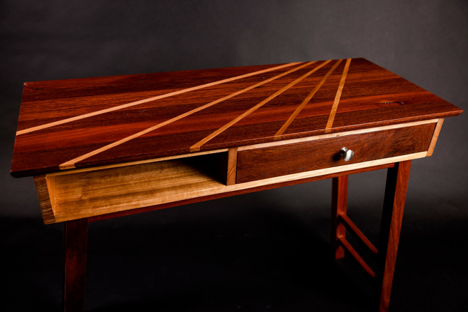 Wooden table with a drawer on the right. A sunray pattern is inlayed on the top