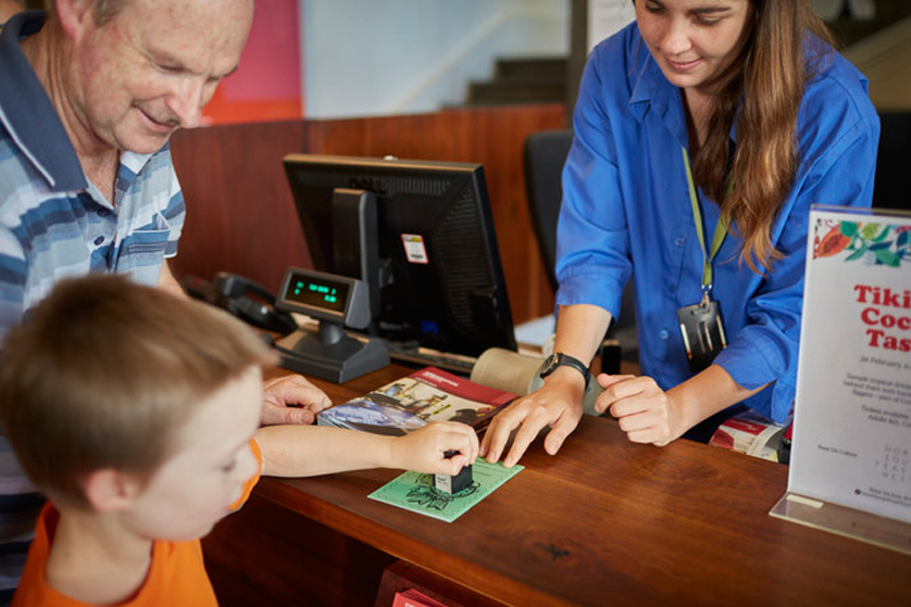 Visitor with a child at the ticketing desk in Immigration Museum.
