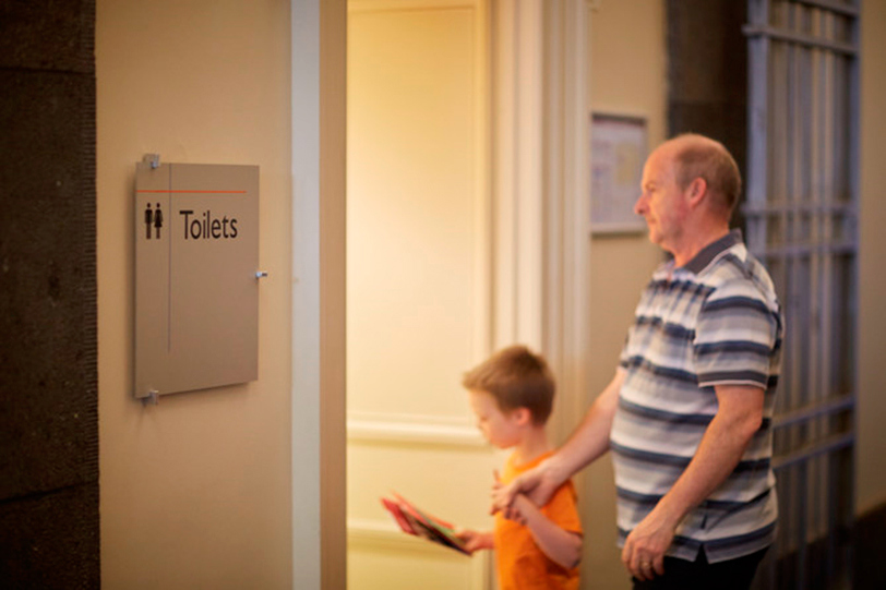 Father and son walking into Bathrooms at Immigration Museum.