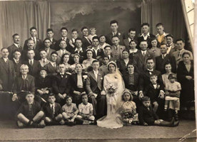 Bride and groom surrounded by family in formal setting