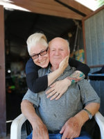 Man sitting being hugged by younger woman.