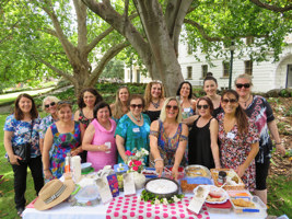 14 people standing behind picnic table in park