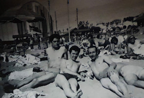 Three young men lounge on the beach