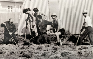 A group of men dig a hole.