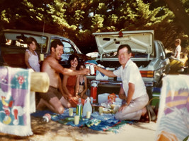 People sitting around picnic blanket.