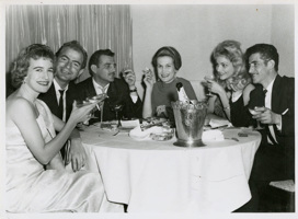 6 people sitting around restaurant table with champagne