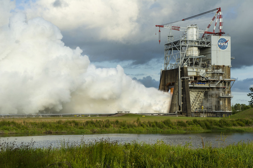 a concrete and metal tower billowing a cloud of steam from its base 