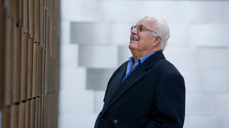 An older visitor views the memorial wall in the Tribute Garden at the Immigration Museum