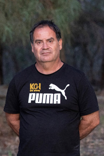 A man standing in a wooded area, seen from the waist up