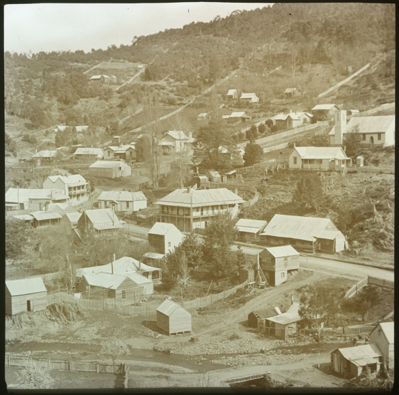 A few buildings, big and small, scattered around the foot of a hill