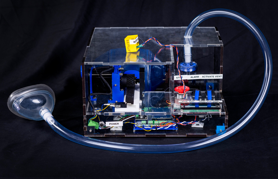 A transparent perspex box, containing various mechanical and electronic components. A large ventilator tube is attached to the top of the box.