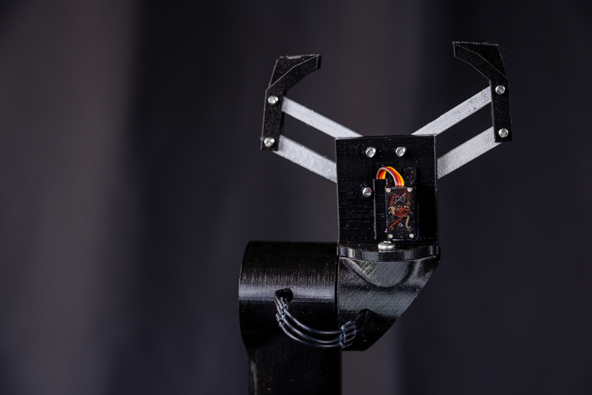 A black robotic arm with two claw like grips protruding at the top.