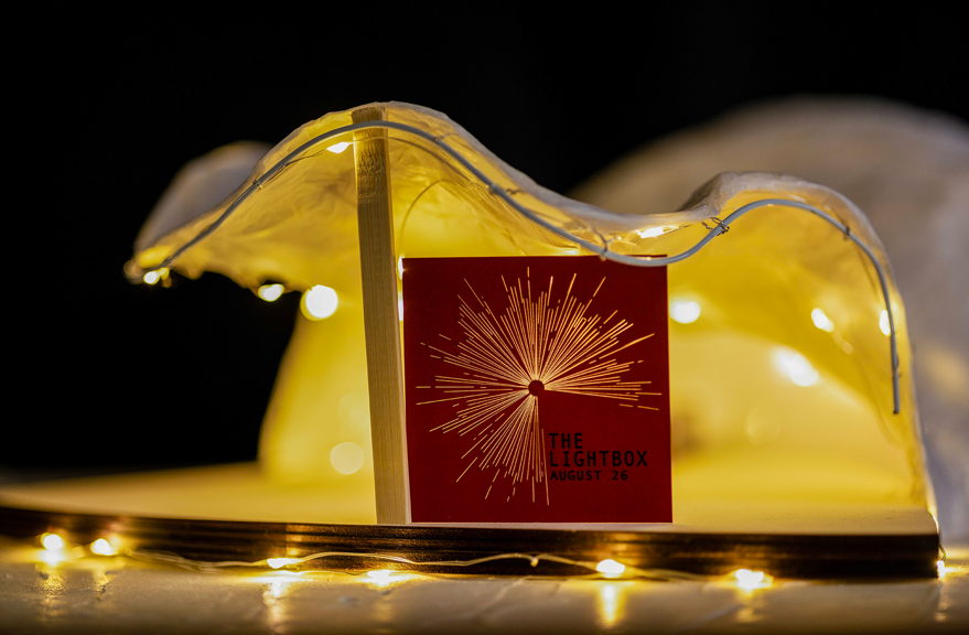 An architectural model of the LightBox Community Stage Space, which is illuminated and has signage that reads ‘The Lightbox August 26.’