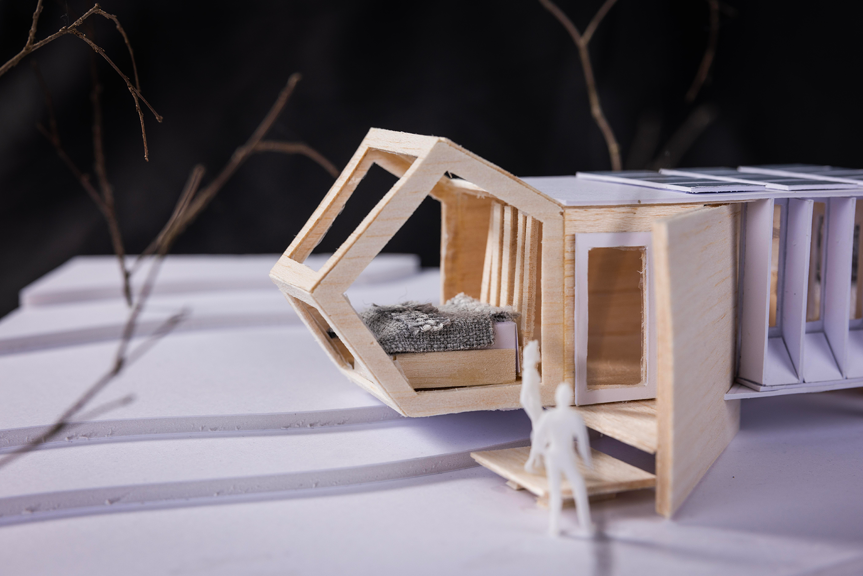 A close-up photo of an architectural model made of plywood and cardboard, with a  geometric structure. 