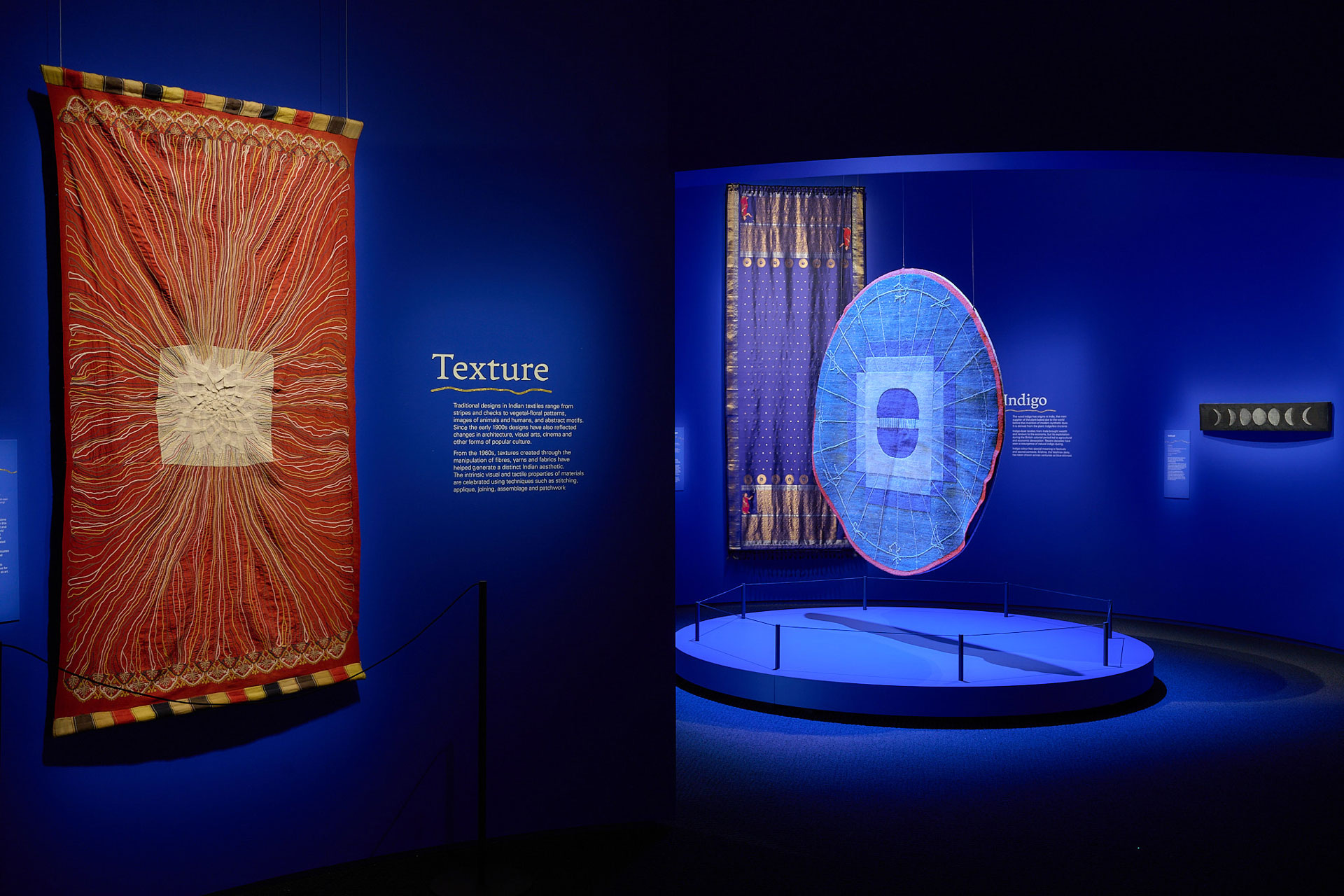Blue exhibition space with textiles hanging on the wall