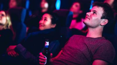 A man holding a beer reclines in a planetarium seat at Scienceworks.