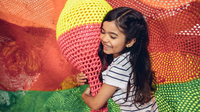 Girl in a climbing net holding onto a rope sculpture