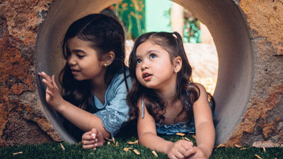 Two girls inside a rock tunnel outside