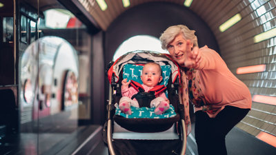 Older Lady with a baby in a pram in the train tunnel exhibition