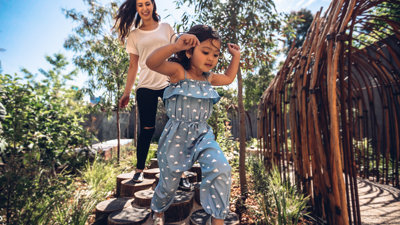 Woman and girl running across stepping stones in garden