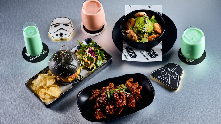 A table at the Star Wars Galactic Café with themed food and drinks. Stormtroopers and diners are sharing the meal.
