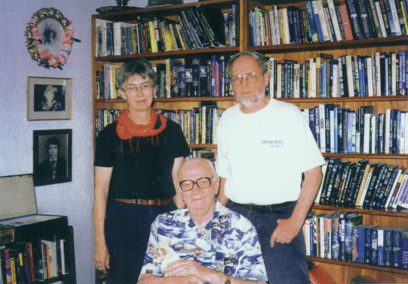 three people posing for a photo in front of a bookcase