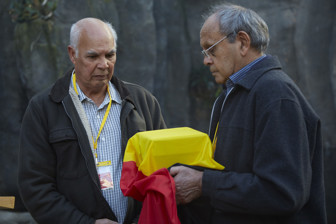 Two men. One man holding a box wrapped in the Aboriginal flag.