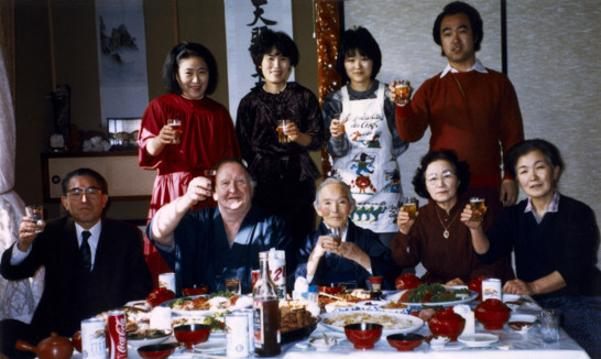 Family gathered around a table laid food.
