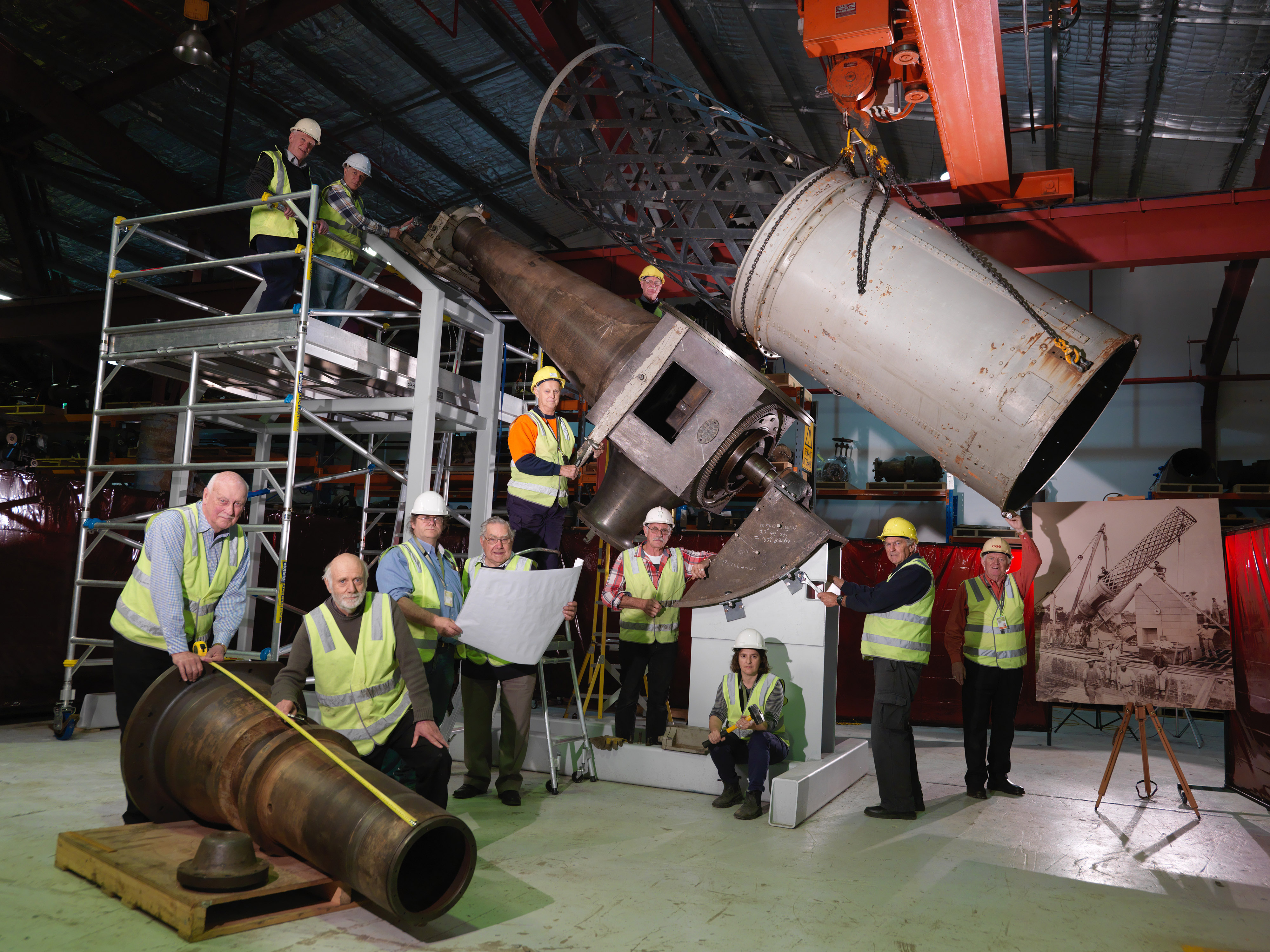 Group of people in high-vis vests standing by a large telescope