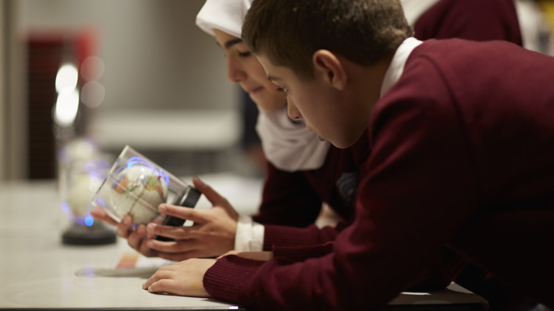 Girl and boy looking at a small globe