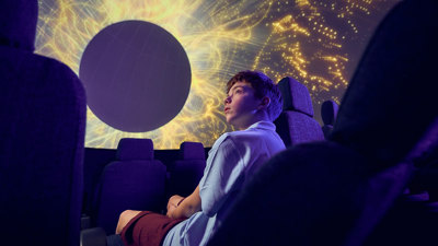 A secondary school student observes a projection of the stars on the dome of the Melbourne Planetarium 