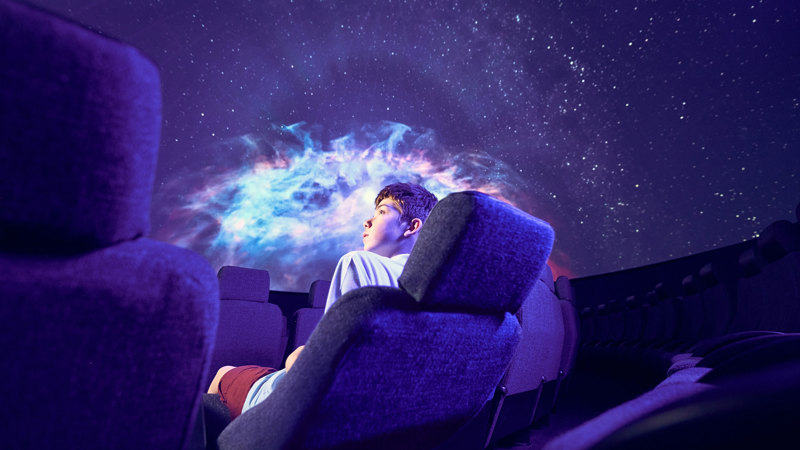 A secondary school student observes projection of a nebula on the dome of the Melbourne Planetarium.