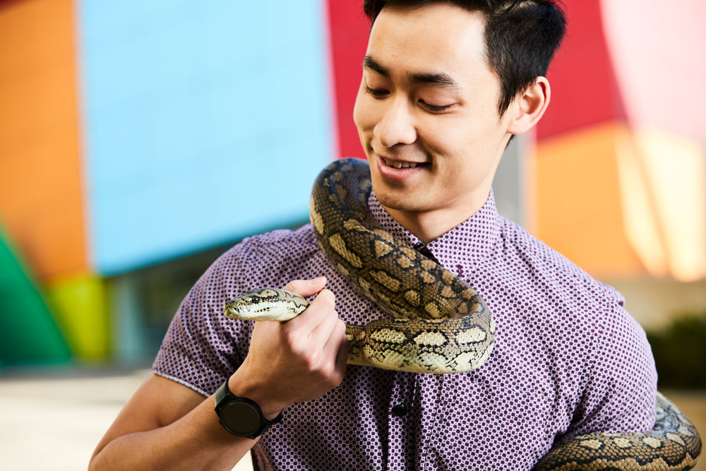 A man smiles whilst holding a snake