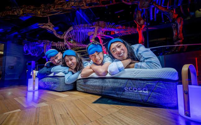 Family wearing sleepwear lying on Ecosa mattresses during Family sleepovers at the Melbourne Museum.