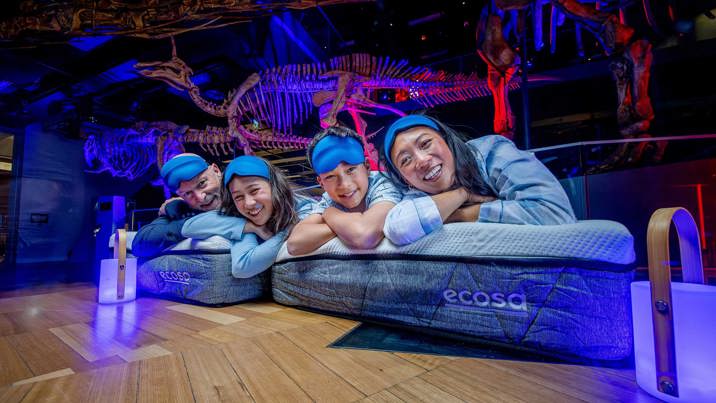 Family wearing sleepwear lying on Ecosa mattresses during Family sleepovers at the Melbourne Museum.